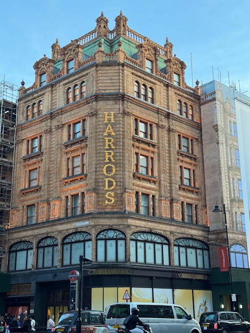 The image depicts the exterior of a historic multi-storey building in Knightsbridge, featuring ornate architectural details and a prominent vertical sign with the word 'HARRODS' in large yellow letter